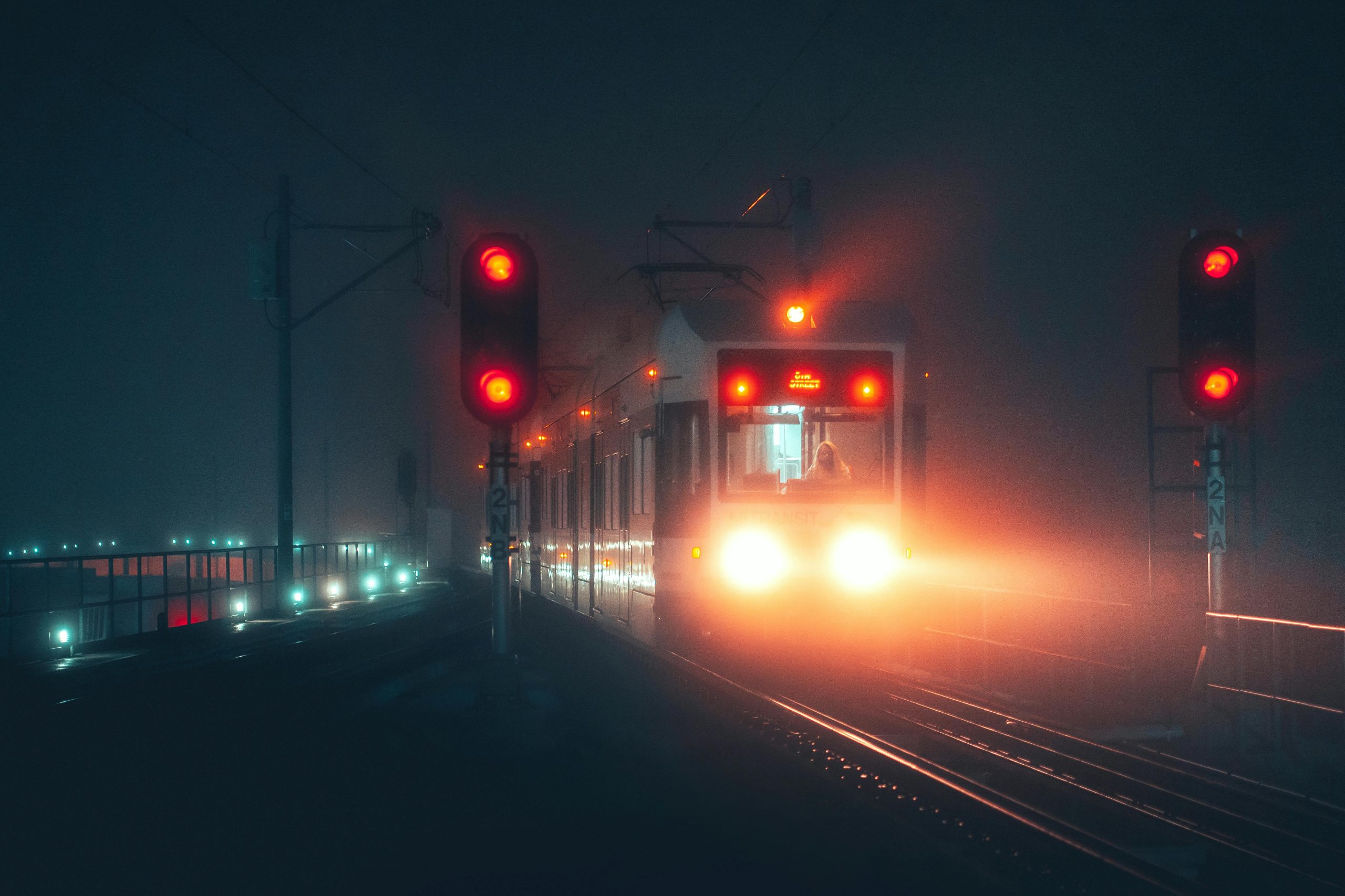 A tram moving through fog at night with glowing signals, creating a mysterious and cinematic atmosphere.