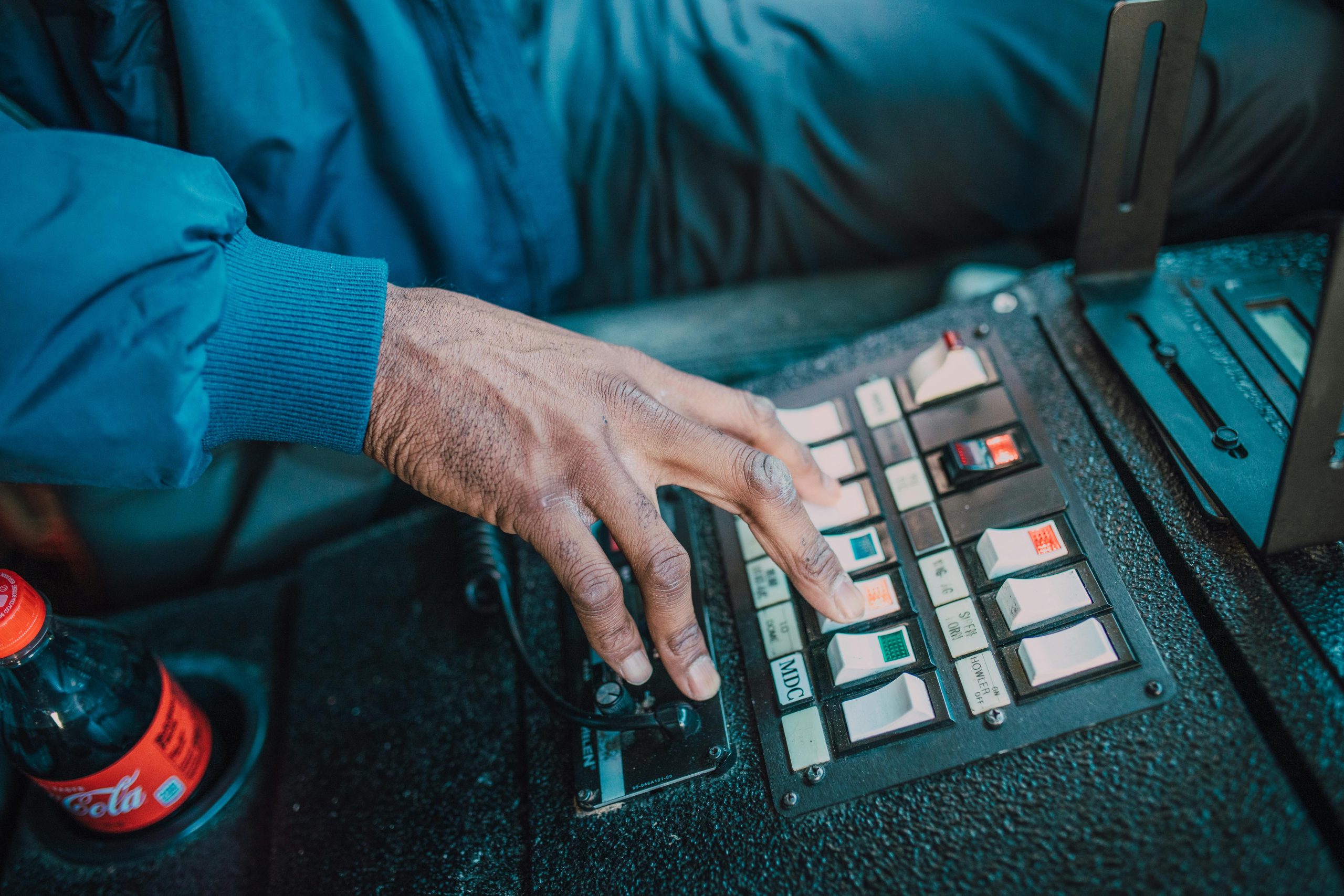 A close-up of a person's hand pressing switches on a vehicle control panel inside a vehicle.