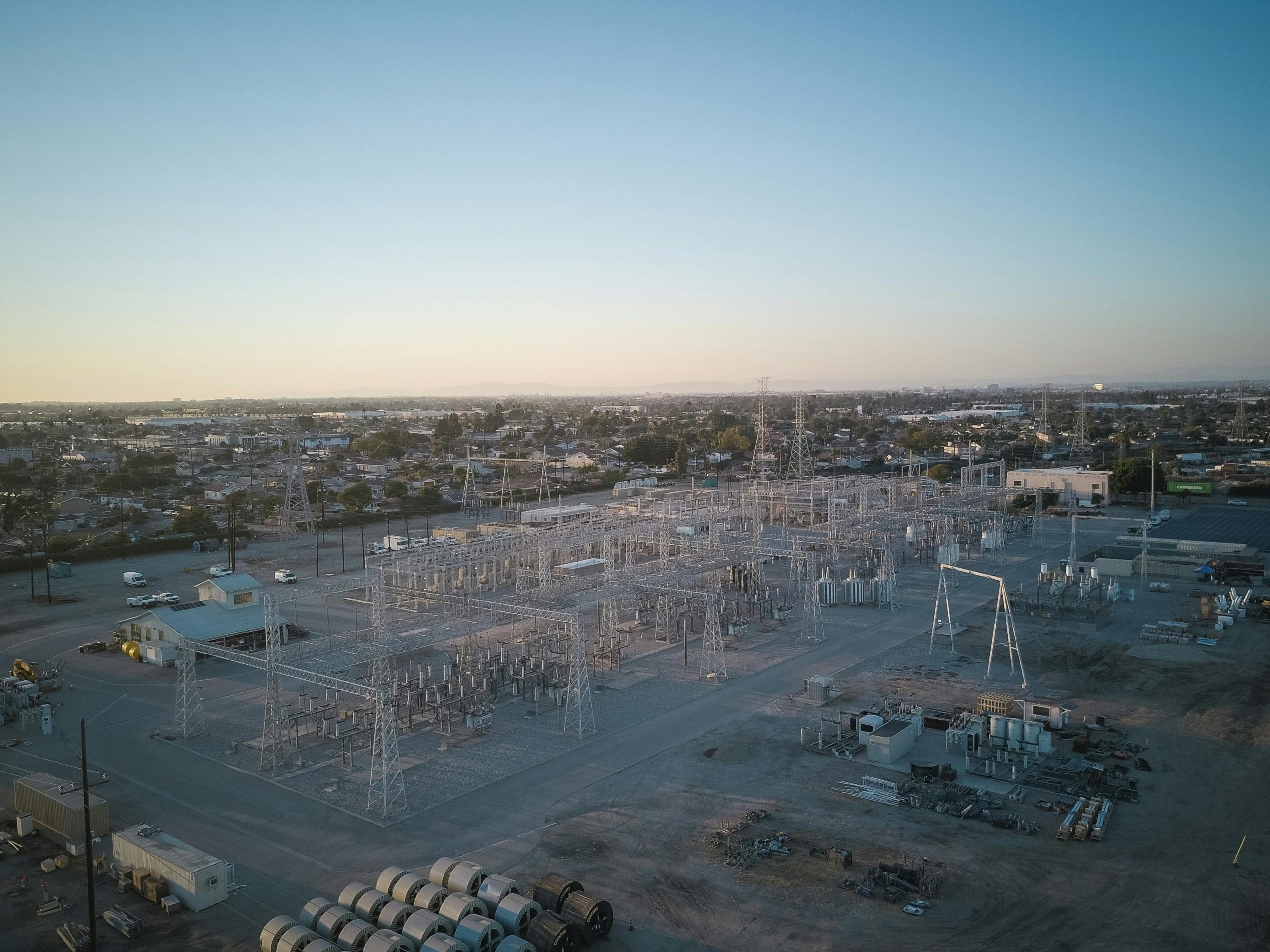 A wide view of a power station showcasing industrial infrastructure under a clear sky at sunset.